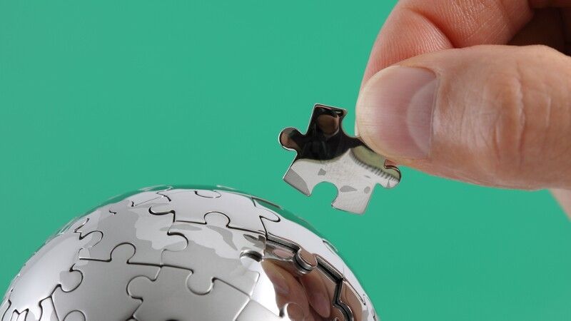 człowiek układa puzzle w kształcie globusu