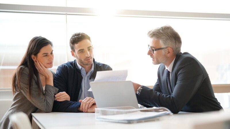 Troje ludzi siedzi przy stole i rozmawia o finansach