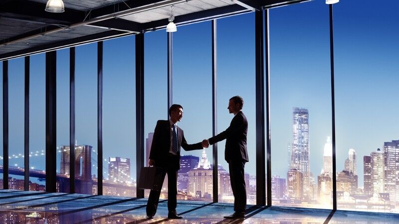 ludzie ściskają sobie dłonie na tle miasta