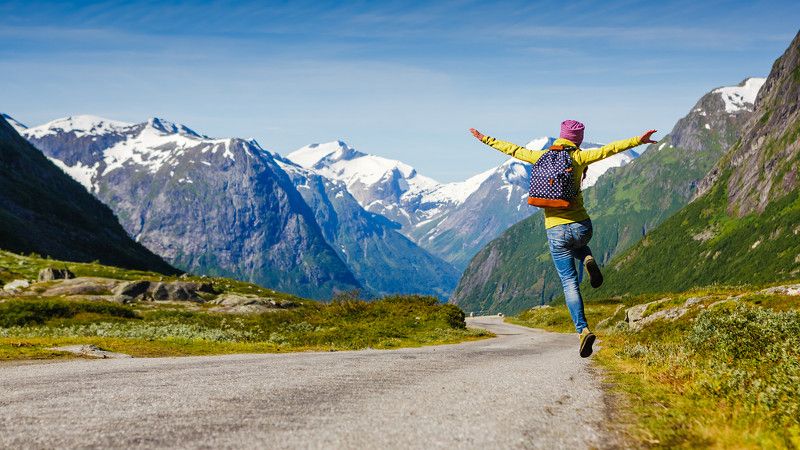 kobieta na drodze w górach skacze z radości