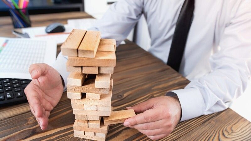 człowiek zabiera klocek z wieży z klocków