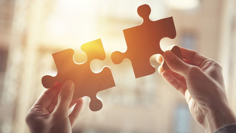 człowiek łączy dwa puzzle na tle zachodzącego słońca